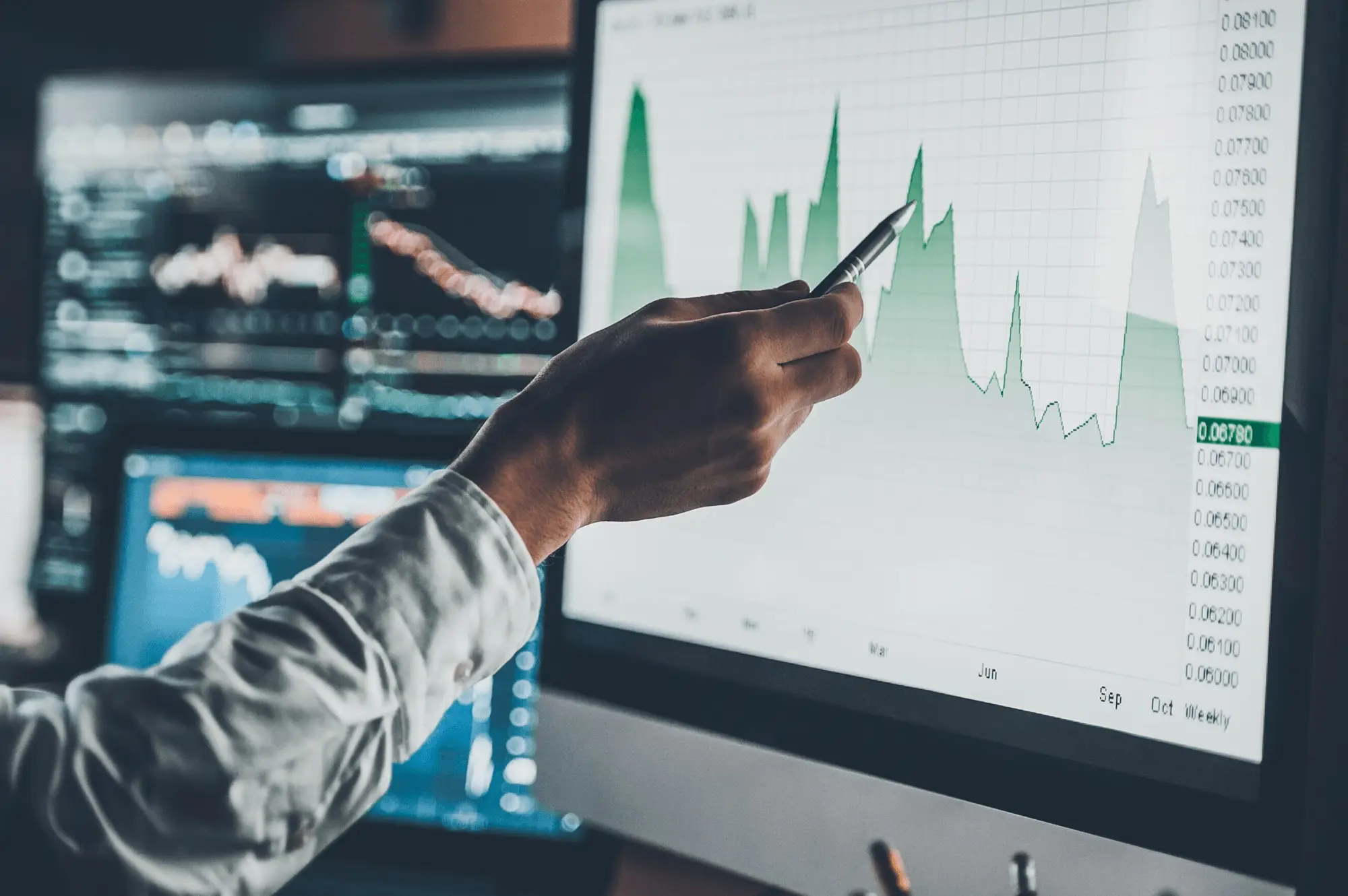 Eine Hand zeigt auf einen dunklen Bildschirm mit Diagrammen und Datenanalysen