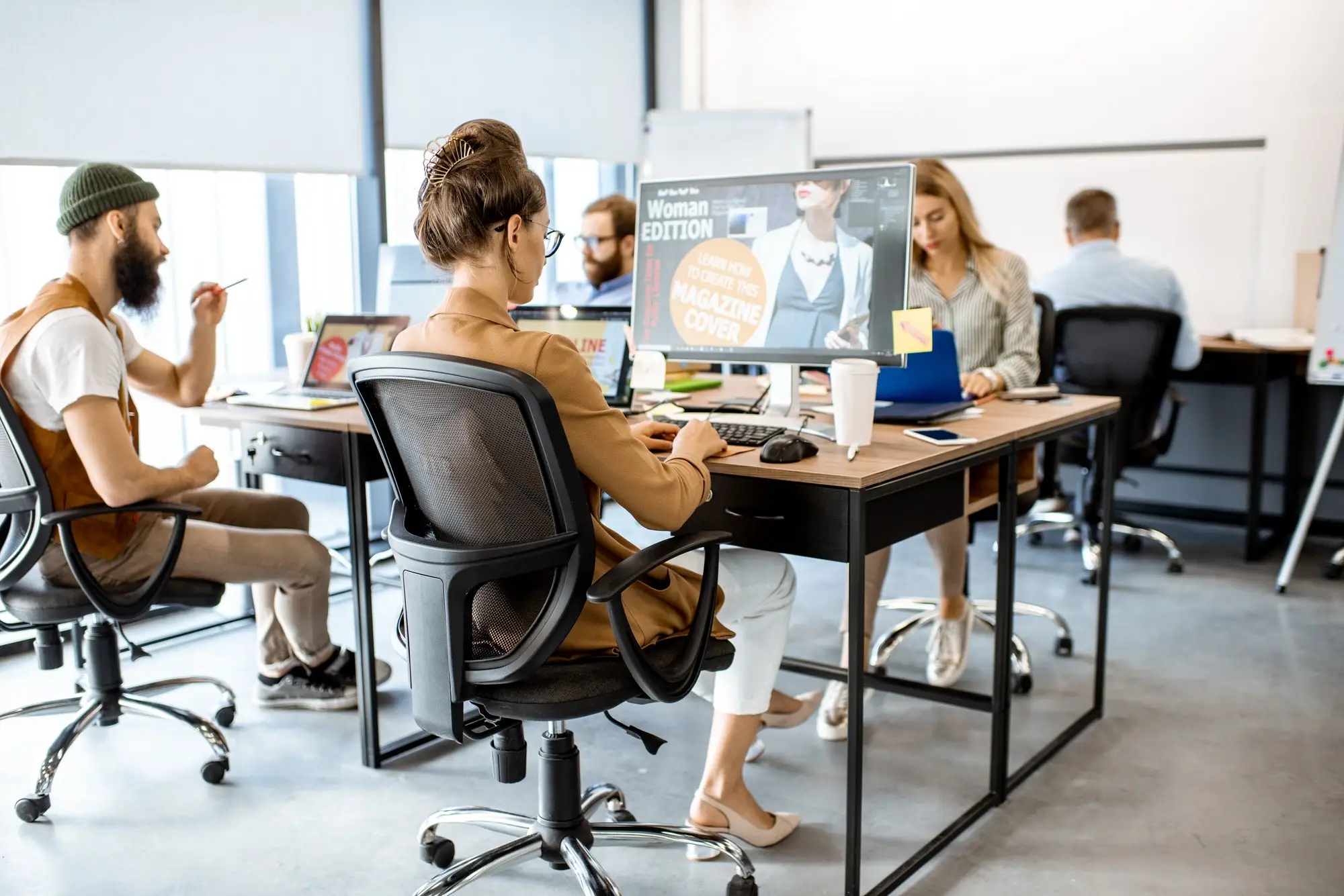Personen arbeiten in einem offenen Büro an ihren Rechnern