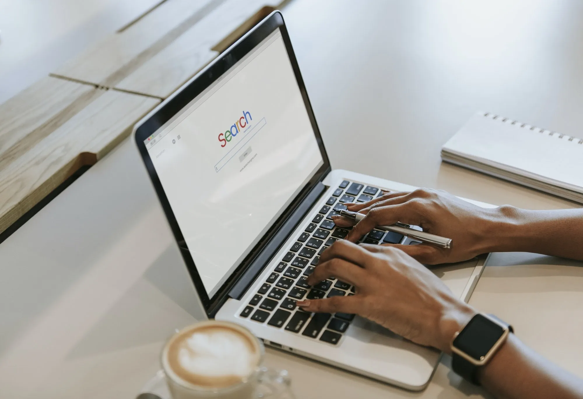 Hände mit Smartwatch tippen auf einer Laptop-Tastatur
