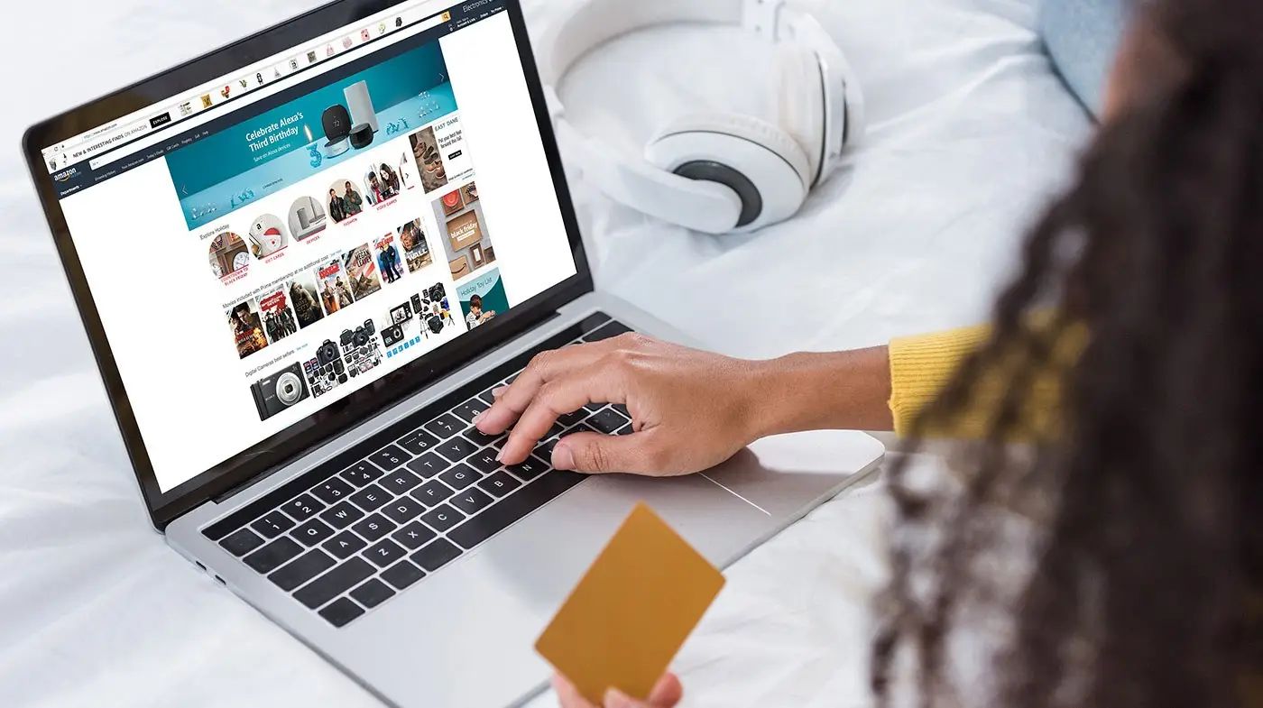Hände tippen auf einem Laptop mit Online-Shop, eine Kreditkarte liegt daneben