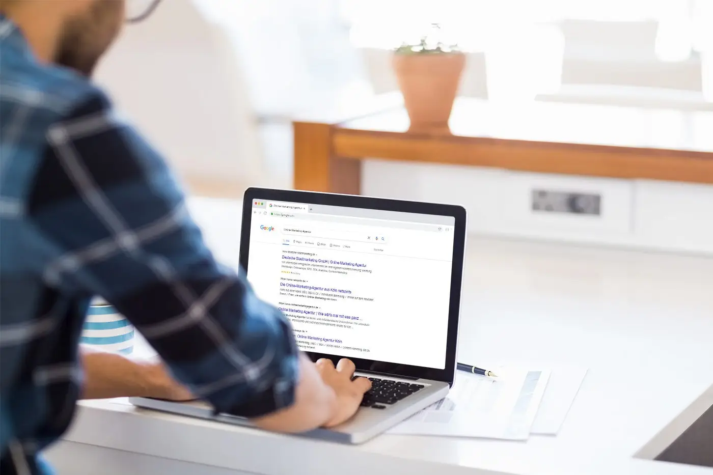 Person an einem Laptop, auf dem Bildschirm eine Google-Suche