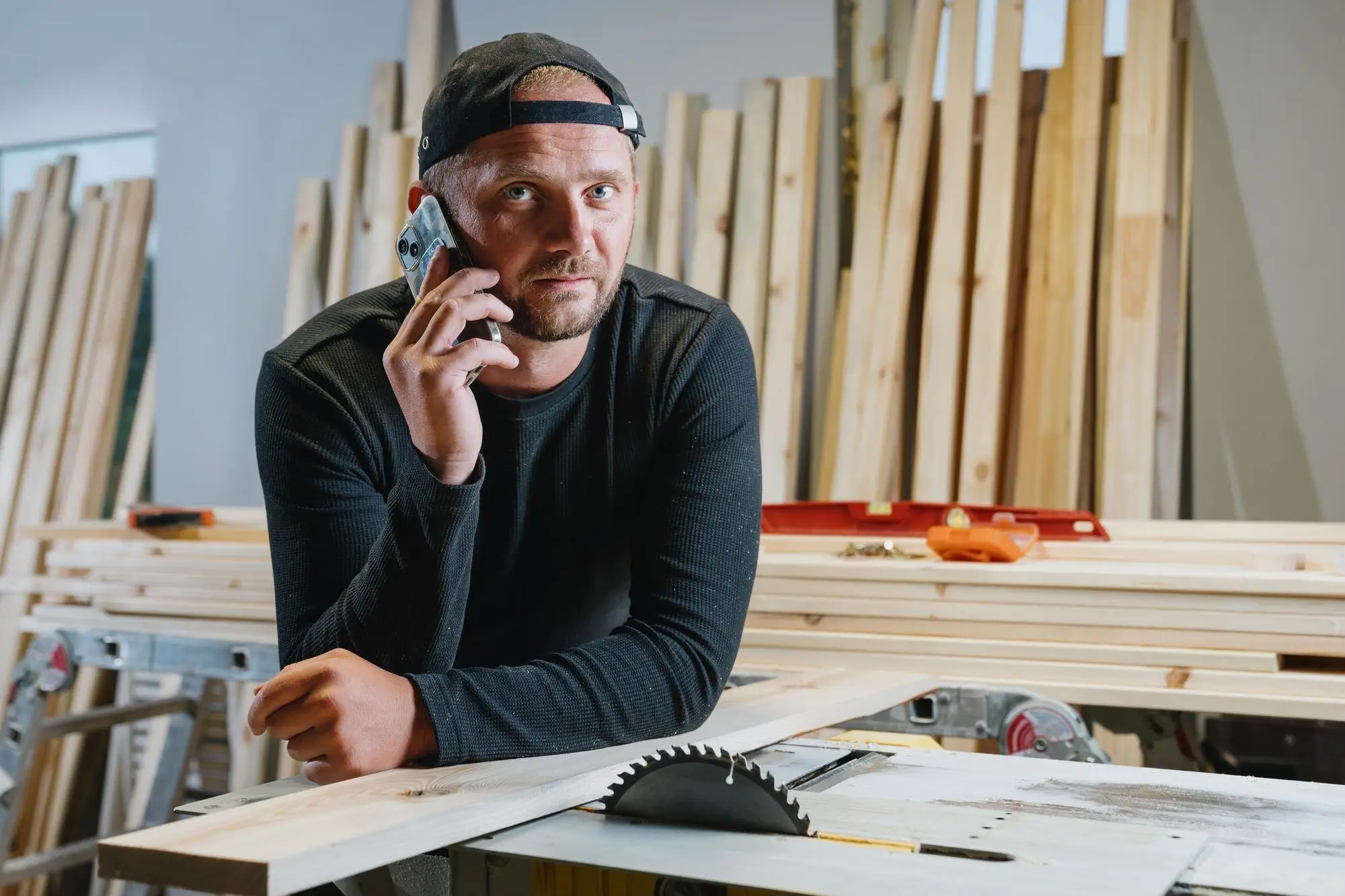 Tischler telefoniert in seiner Werkstatt und hört konzentriert zu