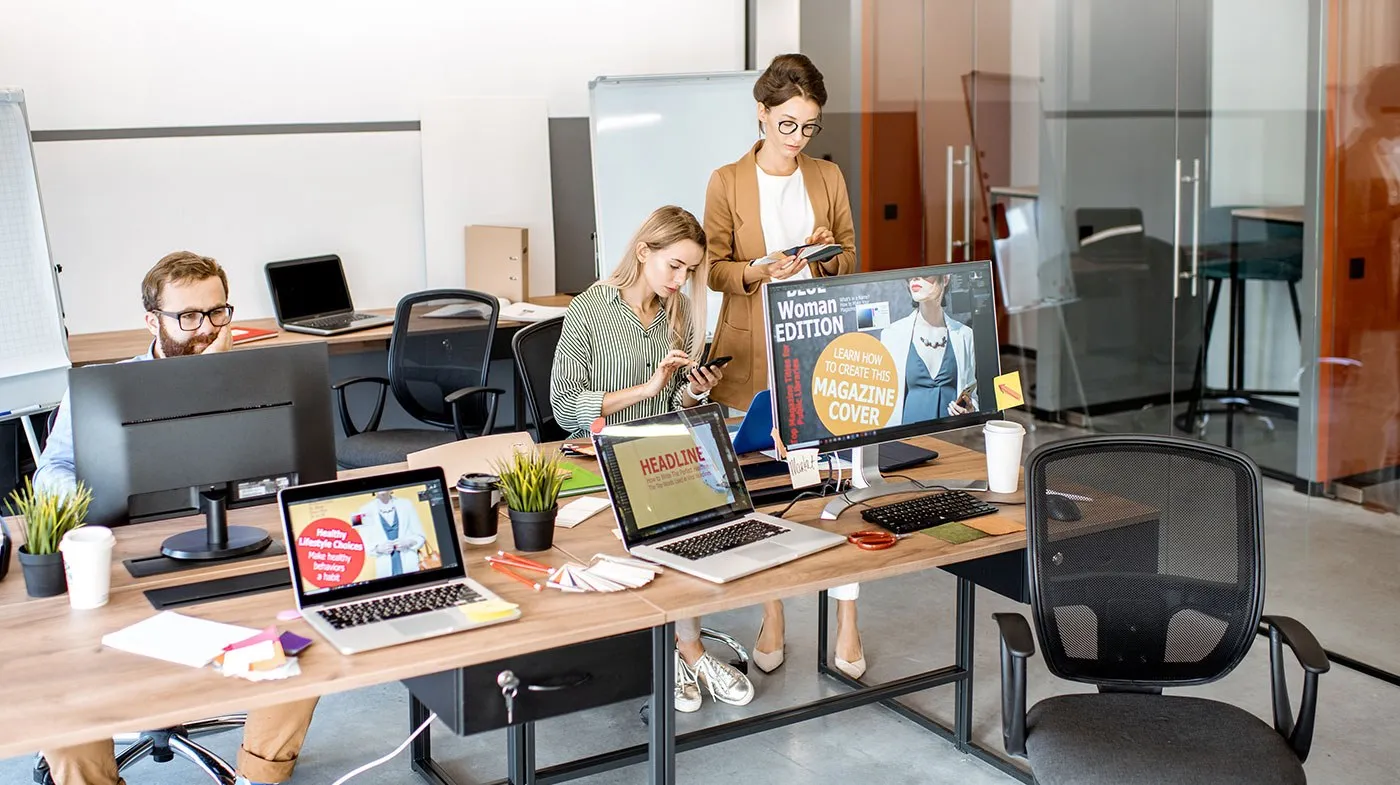 Mitarbeiter arbeiten in einem Büro an Computern mit mehreren Bildschirmen