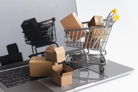 cyber-monday-shopping-sales Miniatur-Einkaufswagen mit kleinen Kartons steht auf einer Laptop-Tastatur – Darstellung von E-Commerce.