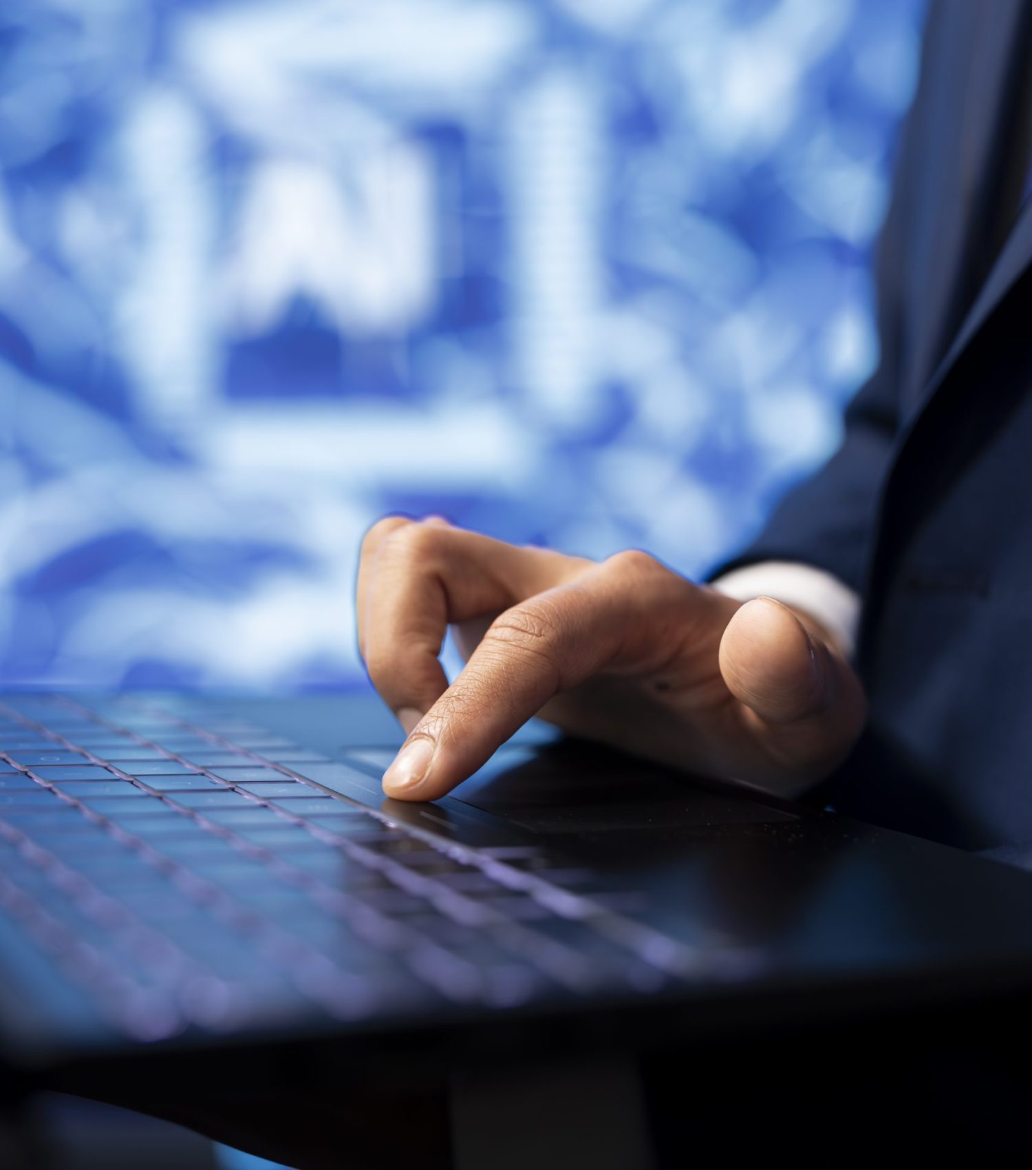 IT specialist coding on laptop, programming artificial intelligence, close up Hand tippt auf Laptop, im Hintergrund ein KI-Symbol.